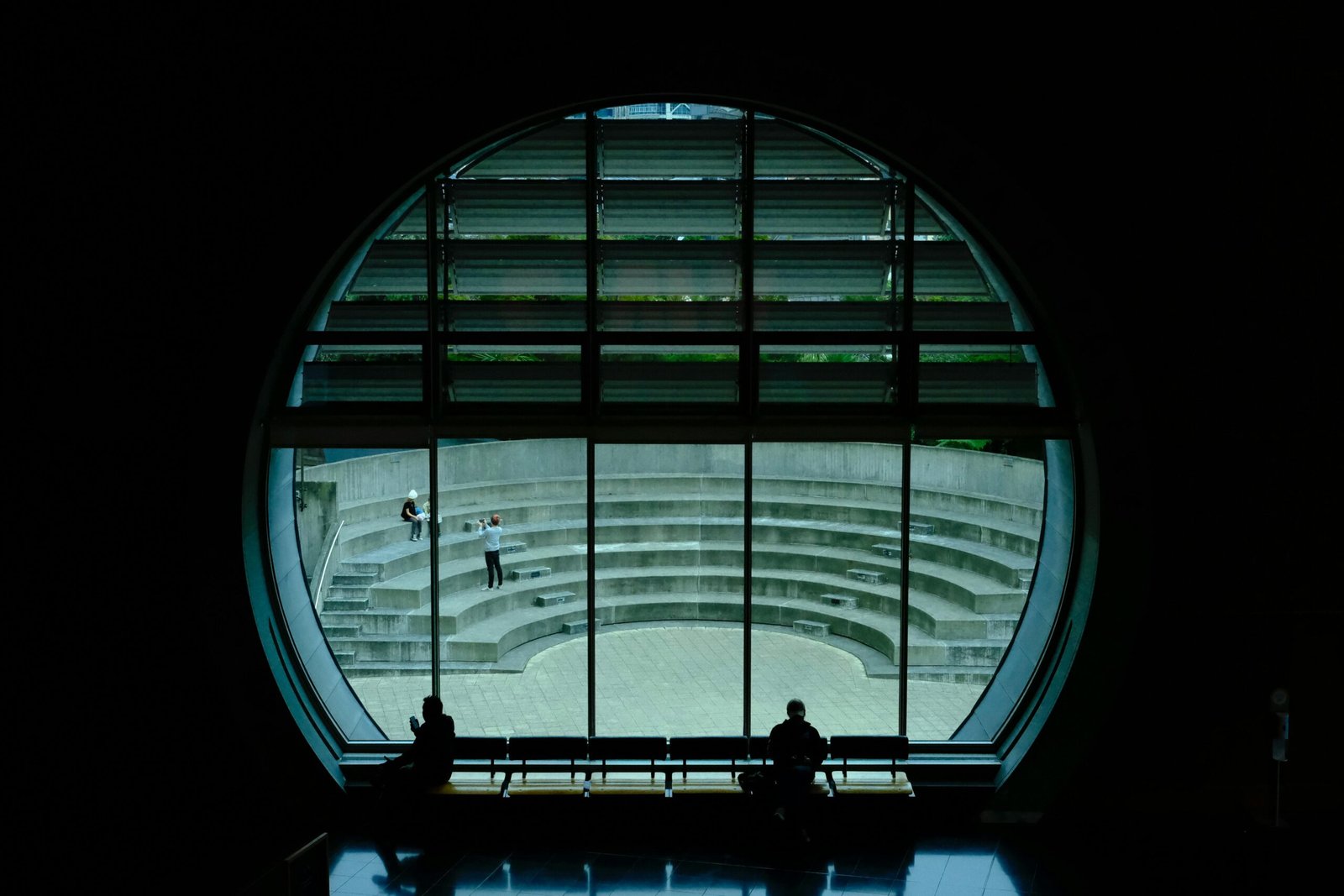 Silhouette of people through a circular window overlooking an outdoor amphitheater in Wellington, New Zealand.
