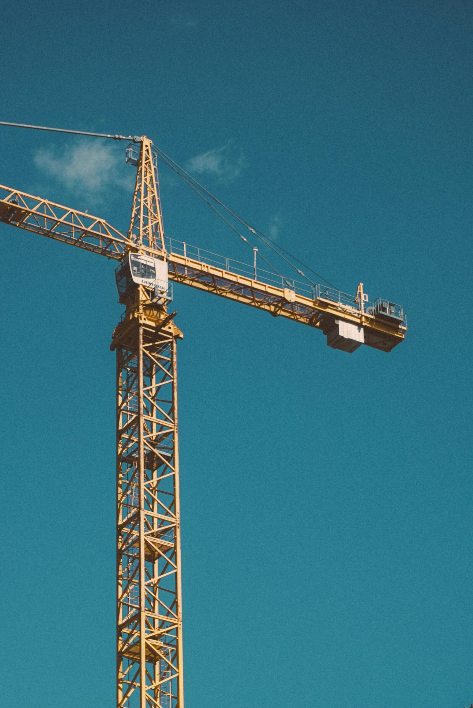 A large construction crane stands tall against a bright blue sky.