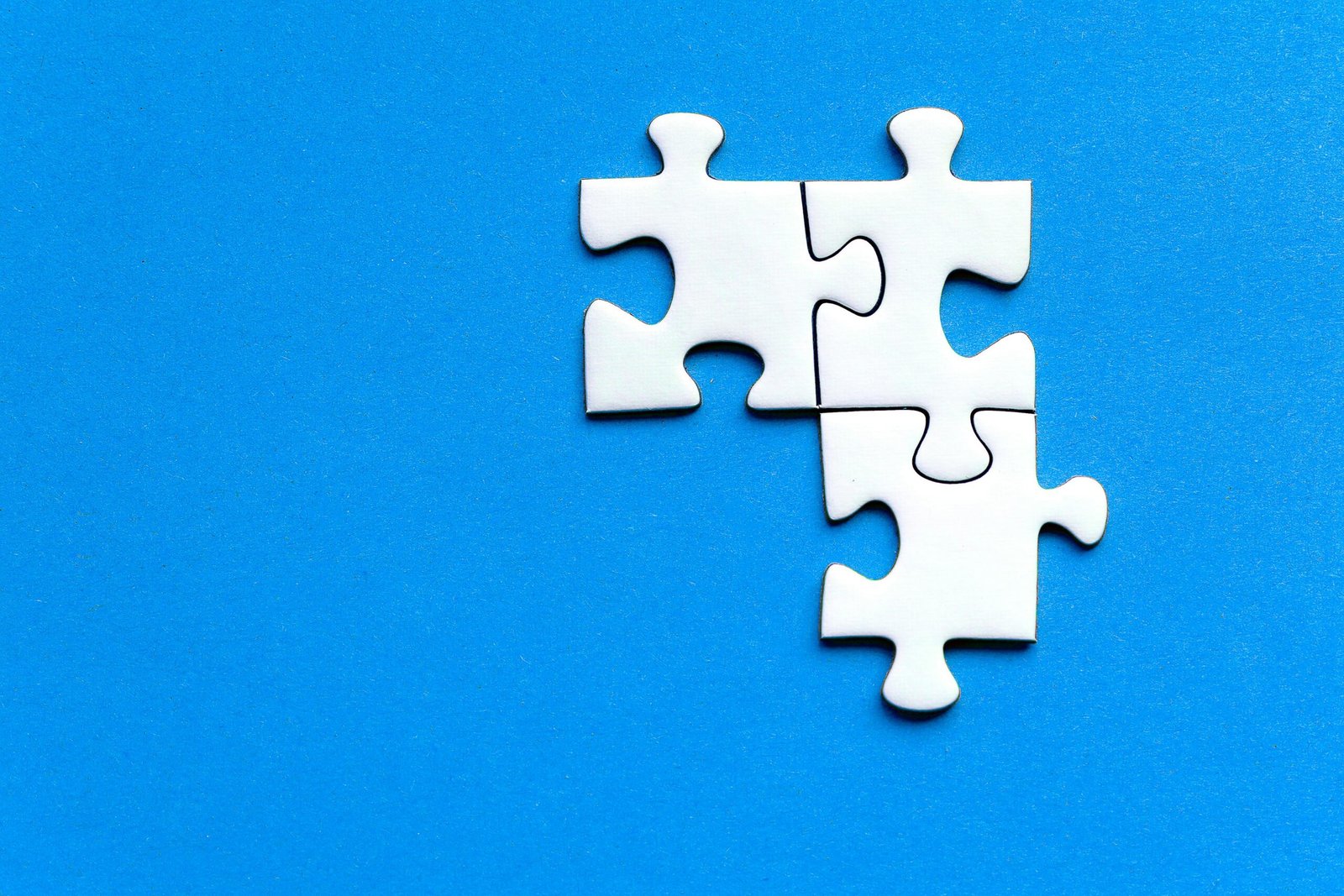 White jigsaw puzzle pieces on a vivid blue background from a top view, perfect for creative concepts.