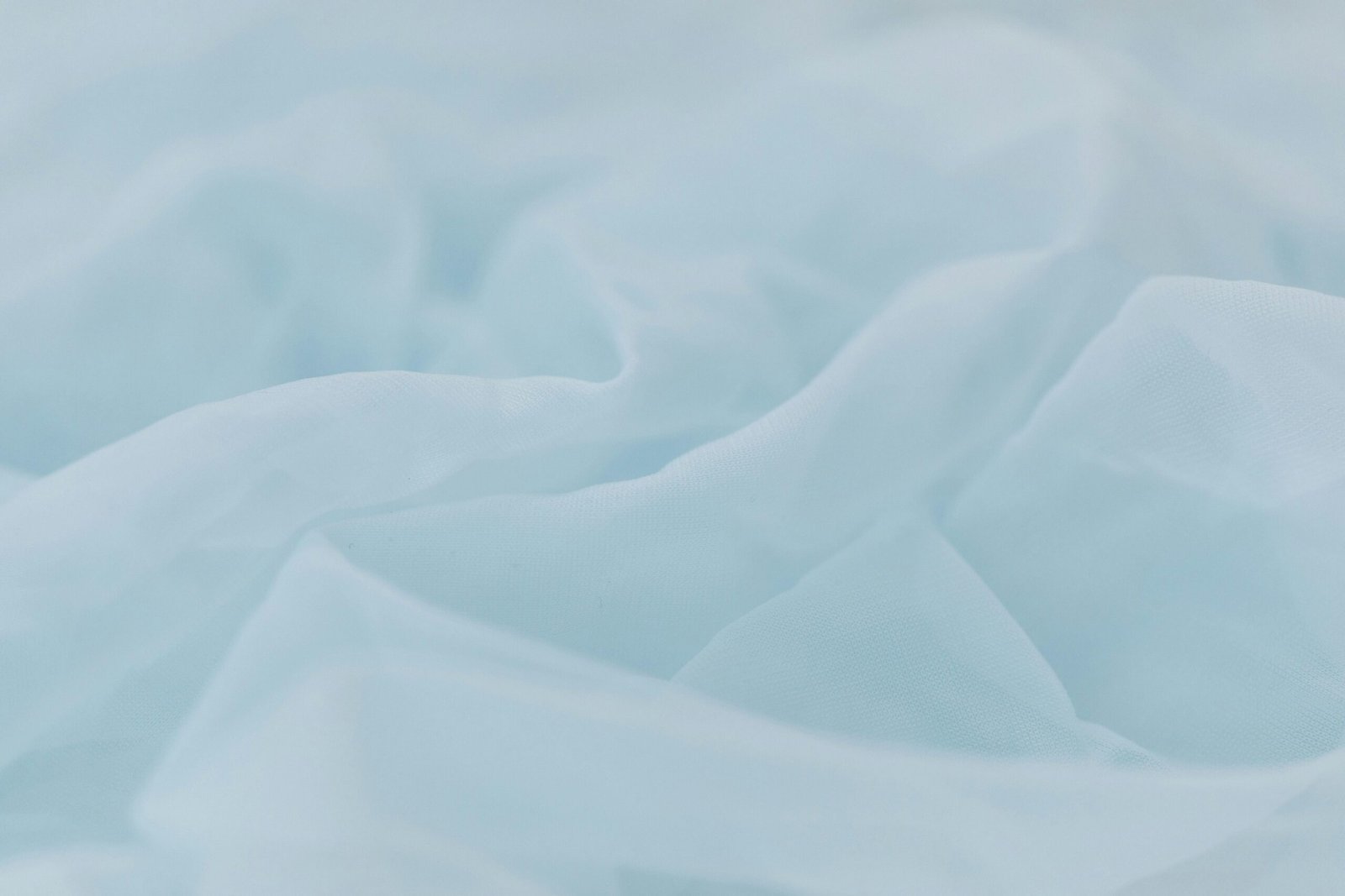 A delicate light blue fabric with rippled texture, ideal for backgrounds or textile themes.