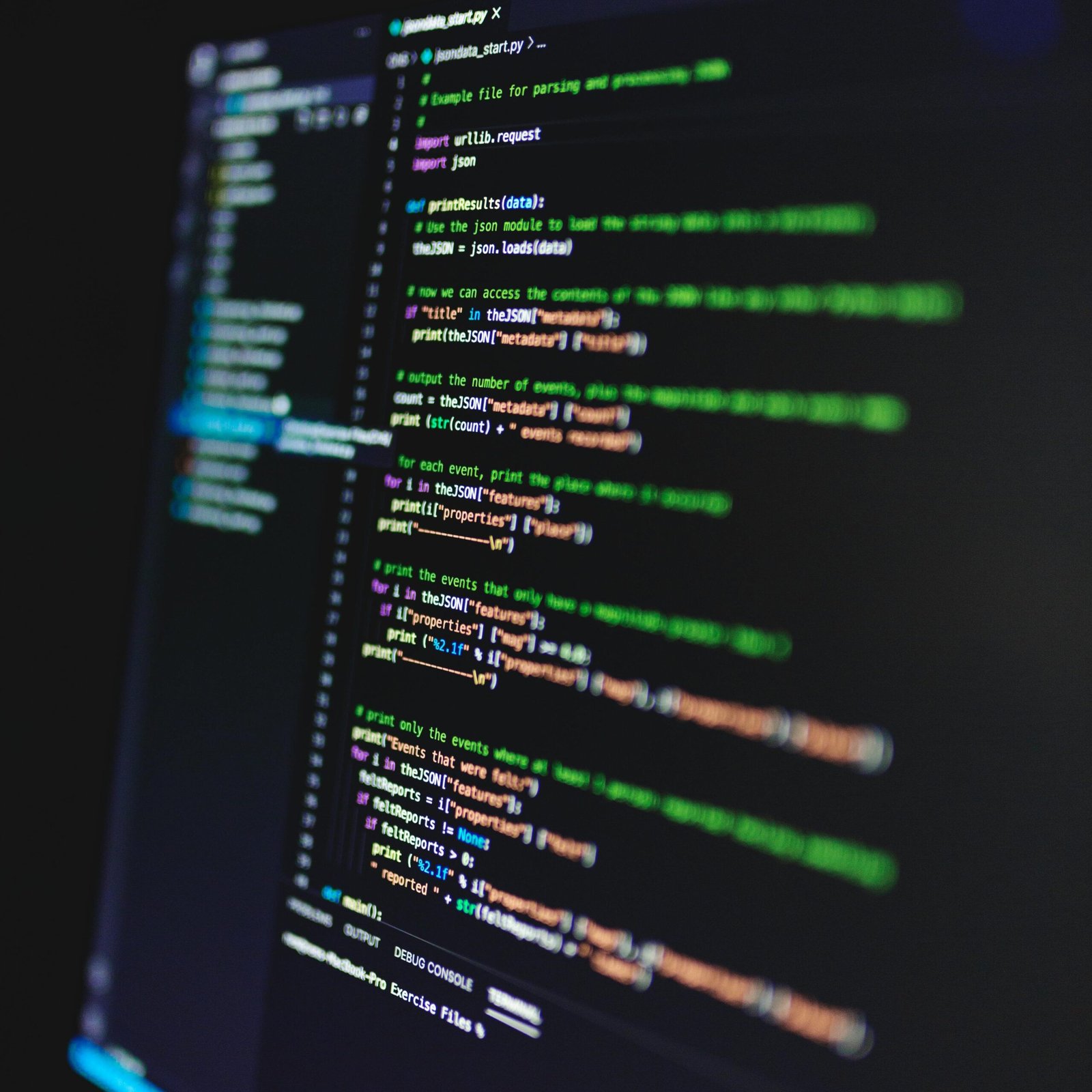 Vertical shot of colorful programming code on a screen in a dark room, highlighting technology work.