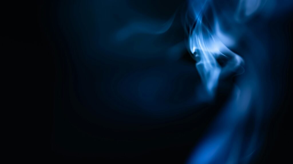 Mystical blue flame and smoke swirling against a dark backdrop, creating a mesmerizing abstract scene.